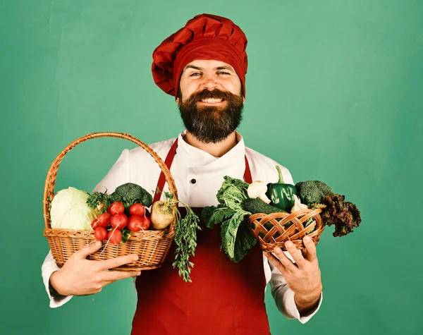 Férfi szakállal zöld háttér. Szakács tart zöldségek — Stock Fotó