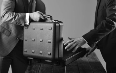 Erkek eller ahşap masada açık siyah çantayı tutar.