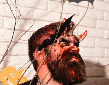 Boynuzlu ve şeytani yüzlü bir şeytan. Korkunç makyaj yapan adam.