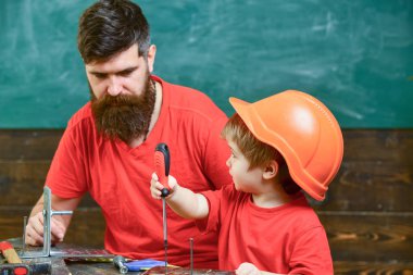 Tamirci ve atölye kavramı. Çocuk, Çocuk koruyucu kask babamla tornavida kullanmayı öğrenme içinde meşgul. Baba, sakallı aracı tornavida kullanmak için küçük oğlu öğretim üst