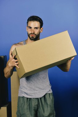 Adam mavi arka plan üzerinde izole karton kutu ile ayakta