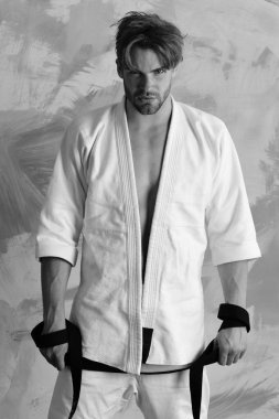 Adam siyah kuşak taşıyan beyaz kimono giymiş.