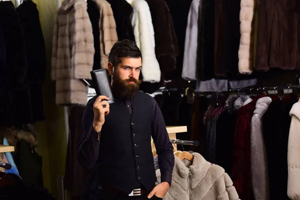 Macho with wallet in front of luxury furry clothes. — Stock Photo, Image