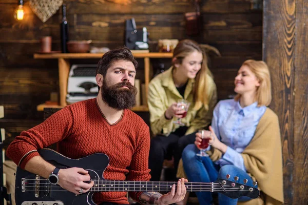 Férfi elegáns szakállal élvezi a kreatív folyamat. Felesége és lánya szórakoztató zenész. Lányok a mosolygó arc hallgató-hoz zene, boldogság fogalmát. Szakállas ember a piros pulóver gitározni — Stock Fotó