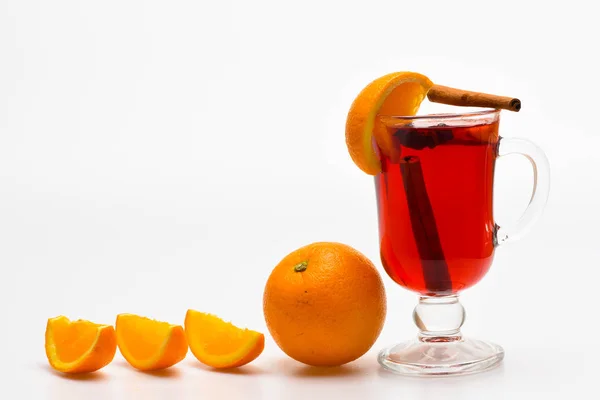 Drink or beverage with orange and cinnamon. Drink and cocktail concept. Glass with mulled wine near juicy orange fruit on white background, close up. Mulled wine with orange juice — Stock Photo, Image