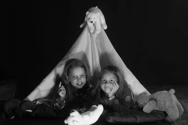 Meninas com rostos astutos jazem sob a tenda cobertor — Fotografia de Stock