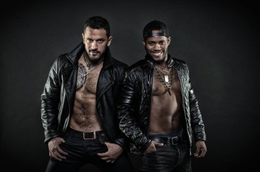 Dövmeli sandıkları ile iki model. Motorcu deri mont içinde. Siyah arka plan üzerine izole rock müzik grubu. Afrika ve Kafkasyalı erkekler seksi organları ile. Acımasız adam şık aksesuarları, moda kavramı giyiyor