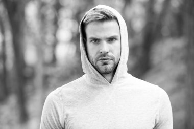 Adam sakallı ve çekici görünüşü hakkında umurunda değil. Ciddi yüz, Doğa arka plan, defocused kıl olan adam. Cilt bakım kavramı. Sakal veya tıraşsız adam görünüyor yakışıklı Kapşonlu adamla