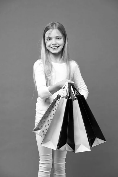 Kid dívka s dlouhými vlasy rádi nakupovat. Dívka na usmívající se tvář nese hrozny nákupní tašky, izolované na bílém pozadí. Dívka ráda koupit módní oblečení v shopping mall. Obchodní koncept — Stock fotografie