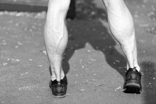 Nogi w czarny sport moda buty na zielonej trawie. Mięśni nóg z żyły na stadion lub arena na słoneczny odkryty. Zdrowia i zdrowego stylu życia. Sport szkolenie i trening — Zdjęcie stockowe