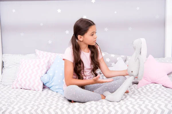 Child play grey rabbit. Best friends. Girl sit bed with grey bunny toy her bedroom. Kid prepare to go to bed. Wish sweet dreams to favorite toy. Girl kid relax and talk to bunny before fall asleep — Stock Photo, Image