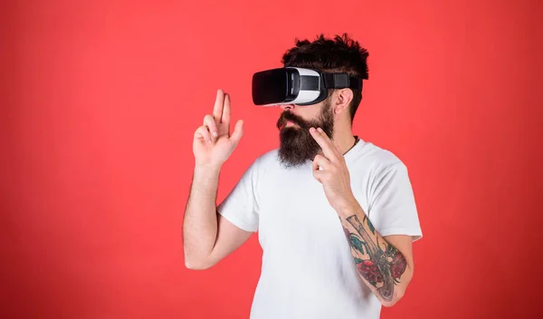 Homem com barba em óculos VR atirando, fundo vermelho. Conceito de galeria de tiro virtual. Hipster em face movimentada jogar em realidade virtual. Cara com cabeça montada tiro exibição com arma na realidade virtual — Fotografia de Stock