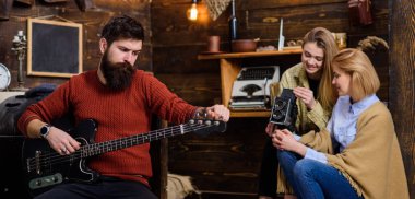 Uzun sakallı ve şık bıyık favori araç ile rahatlatıcı olan adam. Sakallı adam elektrik gitar, müzik ve meditasyon kavramı ayarlama. Karısı ve kızı için yeni şarkı performans hipster