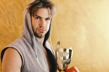 Gri kolsuz kapüşonlu adam altın ödül tutar