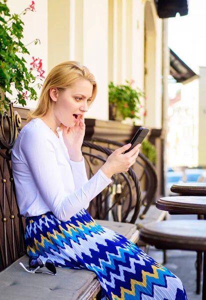 Shocking content. Girl communicating with friend using smartphone. Woman surprised face surfing internet smartphone cafe terrace urban background. Lady surfing internet white spend time in cafe