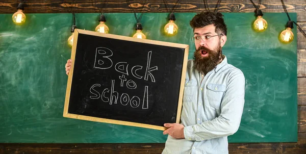 Ausbildung und Studium Konzept. Lehrerin mit Brille hält Schultafel mit Titel zurück in die Schule. Mann mit Bart und Schnurrbart im schockierten Gesicht begrüßt Studenten, Kreidetafel im Hintergrund — Stockfoto