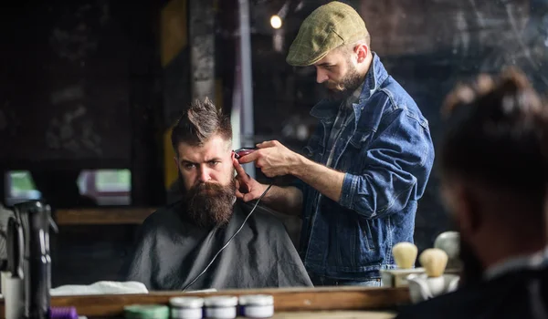 Kapper met clipper trimmen onthaarde nek voor client. Hipster levensstijl concept. Hipster client krijgen kapsel. Kapper met haartrimmer werkt op kapsel van bebaarde man barbershop achtergrond — Stockfoto