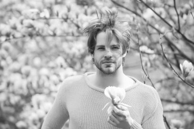 Sakallı, sarı süveterli, çiçekli bir maço.