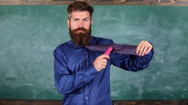 Okul kırtasiye. Adam pis kullanmak zımba tehlikeli bir yol. Öğretmen adam pembe zımba kara tahta arka plan ile sakallı. Okul kaza önleme. Yenilikçi öğretmen formal giyim kravat zımba tutar
