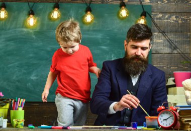 Sanat ders kavramı. Sakallı öğretmeni, sınıfta, kara tahta arka plan çizmek için küçük oğlu baba öğretir. Neşeli çocuk ve resim, çizim öğretmen. Yetenekli sanatçı oğlumla vakit geçirmek