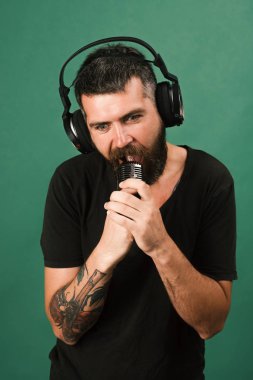 Şarkıcı sakal ve sürpriz yüz ile müzik dinliyor.