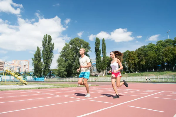 Young family promoting healthy lifestyle. Woman and man run stadium. Couple runners training outdoors. Couple or family live healthy lifestyle. Coach and sportsman motion run training before race — Stock Photo, Image