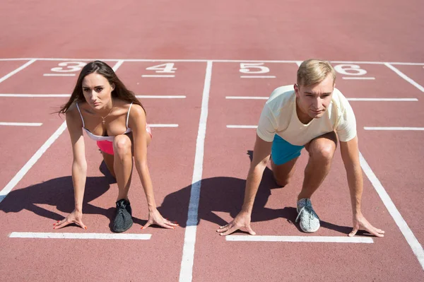 Uguale concetto di forze. Uomo e donna posizione di partenza bassa stadio superficie di corsa. Gara di corsa o gara di genere. Sportivo più veloce raggiungere la vittoria. Sfida sportiva per coppie. Tutti hanno la possibilità — Foto Stock