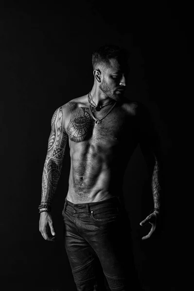 Tatuato uomo mostra torso muscolare sexy. Sportsman con sei pack e ab. Culturista con bicipiti e tricipiti. Modella con tatuaggio in jeans. Cura del corpo con fitness e sport, in bianco e nero — Foto Stock