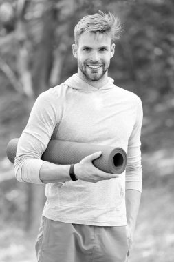 Yoga mat ile eğitim sporcu. Yoga kavramı zamanı. Adam atlet mutlu yüz germe için doğa arka plan gidiyor yoga mat, taşır. Fitness izci ve germe için hasır ile sporcu