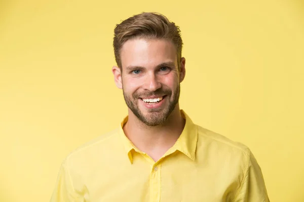 Sorriso brilhante. Homem sorridente rosto posando fundo confiantemente amarelo. Homem consultor loja parece alegre confiante e hospitaleiro. Um tipo com cerdas, feliz em ajudar-te na loja. Emoções sinceras — Fotografia de Stock