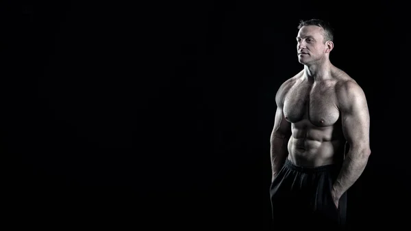 Mann muskulösen Oberkörper posiert selbstbewusst schwarzen Hintergrund, kopieren Raum. Bodybuilder Errungenschaft große Form. Bodybuilder verspannte Muskeln sieht attraktiv aus. Tolles Körperergebnis durch regelmäßiges Fitnesstraining — Stockfoto