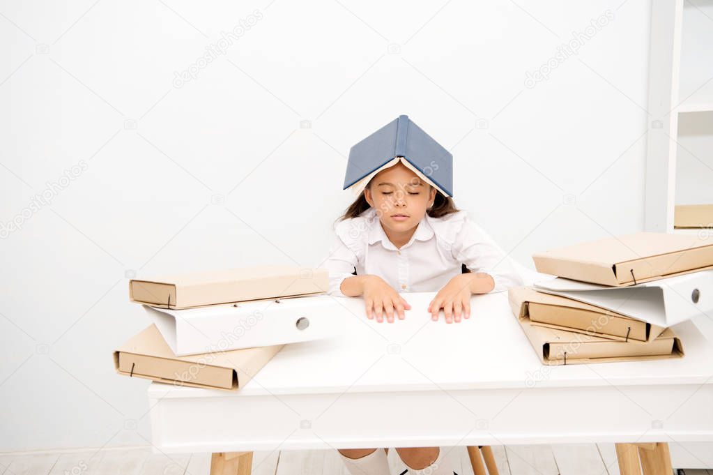 Overloaded with tasks. Girl child exhausted book roof head white background. Schoolgirl tired of reading and studying. Kid school uniform tired sleepy face. Schoolgirl fall asleep while studying