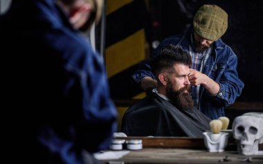 İstemci, defocused kesme makinesi kırpma saçlı yansımanın berberin. Hipster istemci Başlarken saç kesimi. Kuaför saç kesme makinesi ile sakallı adam, salon arka plan saç kesimi üzerinde çalışır. Erkeklik kavramı