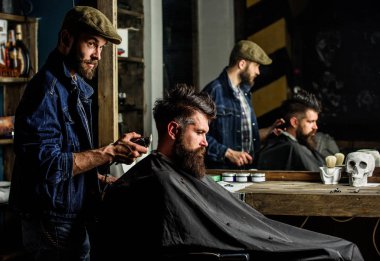 Styling saç kesme makinesi ile acımasız sakallı istemcisinin berber. Kuaför saç kesme makinesi ile saç modeli sakallı adam berber arka plan için çalışır. Hipster istemci Başlarken saç kesimi. Hipster yaşam tarzı kavramı