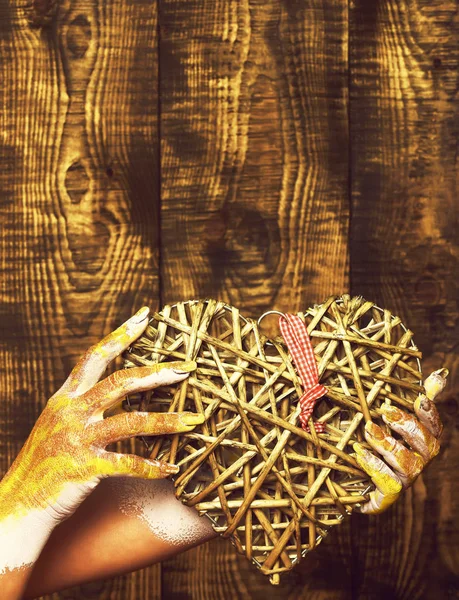 Жіноча рука намальована золотою фарбою або блистером, що тримає декоративне сіре серце валентинки на коричневому вінтажному студійному фоні, копіювати простір . — стокове фото
