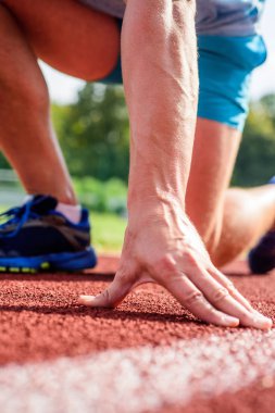 Koşucu yakın gitmeye hazır. Esneklik eklem aralığı hareketi sınırlamak için streç yeteneğidir. Koşucular için ek kaygı. Nihai ilaçlar. Sporcu koşu parkuru düşük üzerinde el başlangıç pozisyonu