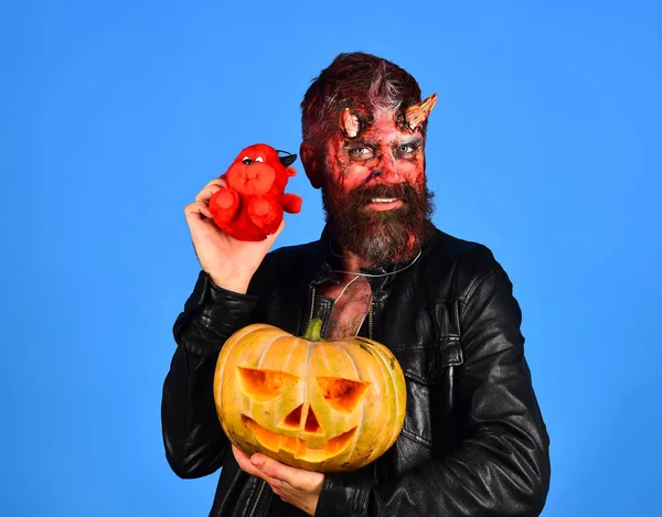 Demon with horns and interested face holds carved jack lantern — Stock Photo, Image