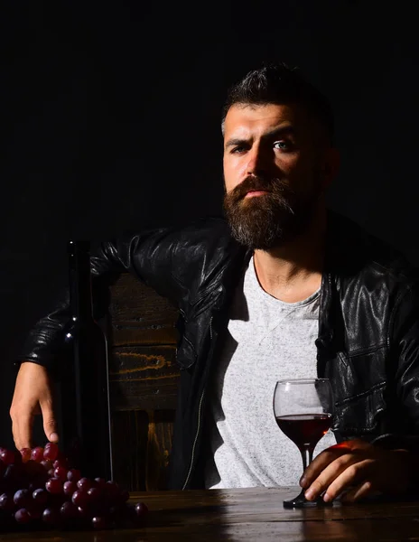 Degustator z dumą siedzi przy butelce wina i winogronach — Zdjęcie stockowe