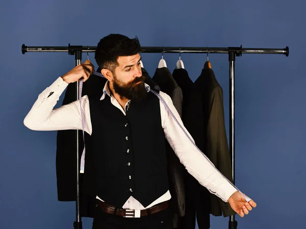 Modern wardrobe choice concept. Man with beard by clothes rack. — Stock Photo, Image