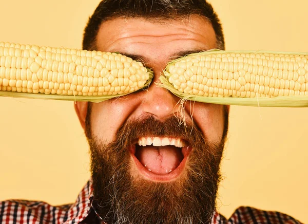 Bauer mit fröhlichem Gesicht hält gelben Mais über die Augen — Stockfoto