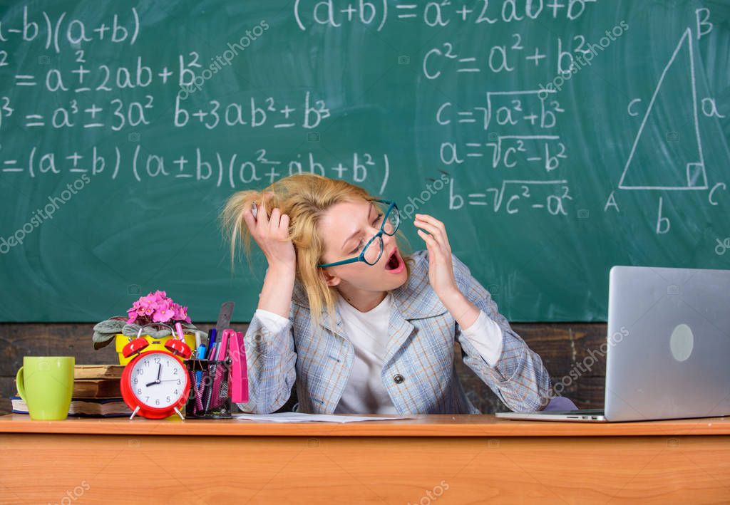 Work far beyond actual school day. Teacher busy with paperwork. Teacher tired face keep work after classes. Workaholic sleepy at workplace. Teacher woman sit table classroom chalkboard background.