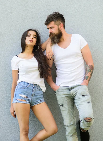 Jeune et élégant. Quelques chemises blanches câlin près du mur gris. Hipster barbu brutal et élégant fille à la mode traîner. Deux amis traînent ensemble. Jeune tenue élégante simple mais moderne — Photo