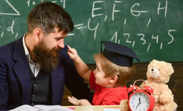 子供の注意欠陥を勉強しながら陽気な気が散る。いたずらっ子のコンセプトです。先生は、鏝板、背景に黒板の生徒。担任の先生の息子は、小さな男の子、髭、父します。 — ストック写真