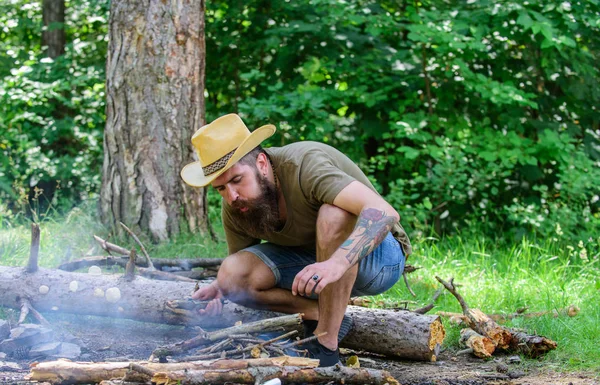 Come costruire falò all'aperto. Disporre i ramoscelli del bosco o bastoni di legno in piedi come una piramide e posizionare le foglie sotto. Guida definitiva ai falò. Uomo cappello di paglia prepara falò nella foresta — Foto Stock