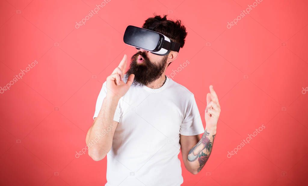 Man bearded hipster with virtual reality headset on red background. Shooting VR game. First person shooter shows how addictive VR could be. Man hand gesture as gun play shooter game in VR glasses