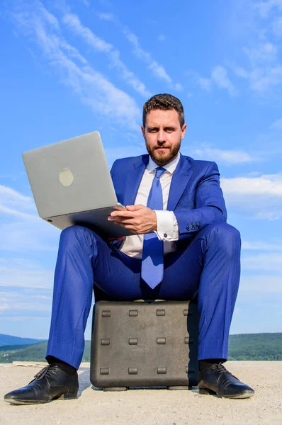 Negocios al aire libre. Hombre de negocios con portátil sentarse maletín azul cielo fondo. Laptop atributo indispensable hombre de negocios moderno. Tecnologías modernas trabajo de oportunidad de dispositivo portátil en todo el mundo — Foto de Stock