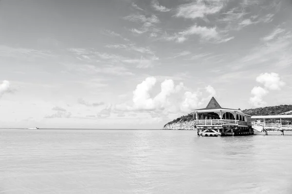 Морской пляж с деревянным укрытием в солнечный день в Антигуа. Пирс в бирюзовой воде на голубом фоне неба. Летние каникулы на Карибах. Странствовать, путешествовать, путешествовать. Путь, открытие, путешествие — стоковое фото