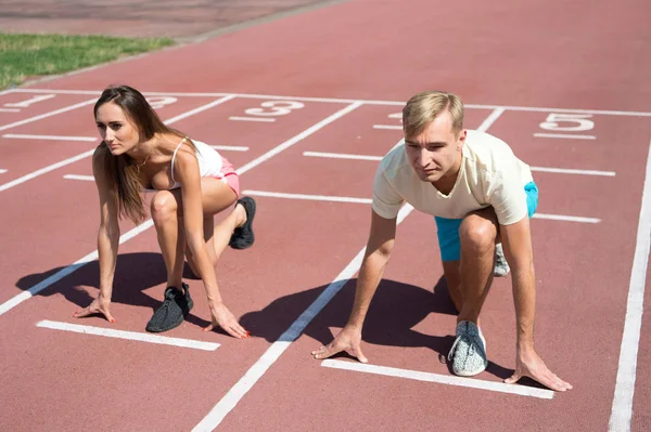 Uomo e donna posizione di partenza bassa stadio superficie di corsa. Gara di corsa o gara di genere. Sportivo più veloce raggiungere la vittoria. Sfida sportiva per coppie. Tutti ne hanno la possibilità. Concetto di forze uguali — Foto Stock