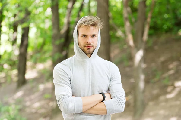 Feeling confident. Guy bearded attractive casual clothes hooded. Man with bristle confident face nature background defocused. Man unshaven guy looks handsome casual hooded. Comfortable means simple