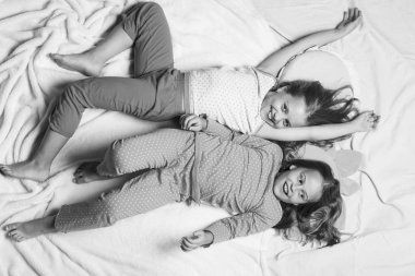 Gülümseyen yüzlü çocuklar pembe arka planda yatıyor.